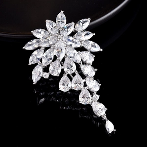 Macro shot of silver flower brooch with pear-cut zirconia and hanging crystal tassels