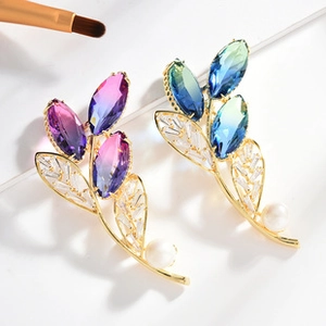 Detail of leaf brooch with tourmaline crystals, zircons and pearls on white background