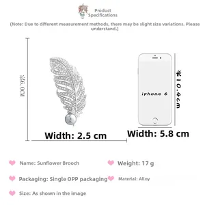 Vue détaillée de la broche plume argentée avec strass et perle grise à côté de l'iPhone