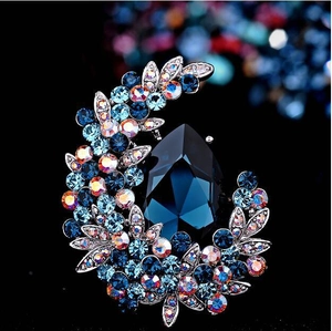 Close-up of sparkling blue pear-cut crystal brooch with silver alloy floral setting