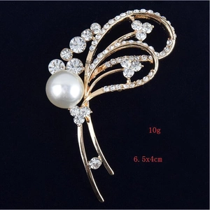 Détail d'une broche florale avec perle et strass mesurant 6,5x4cm pour un poids de 10g