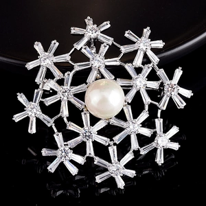 Macro shot of snowflake brooch with center pearl and sparkling cubic zirconia stones