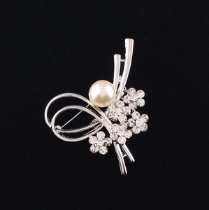 Gros plan détaillé d'une broche florale argentée avec perle blanche et strass brillants