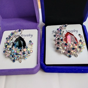 Detail of luxury Austrian crystal brooches in red and blue pear-shaped stones with gift boxes