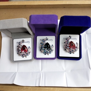 Detailed macro view of pear-cut crystal brooches in velvet gift boxes