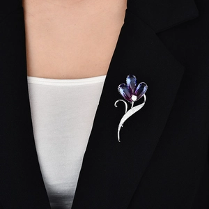 Detailaufnahme der Kristall-Blumenbrosche mit lila Farbverlauf auf einem schwarzen Sakko