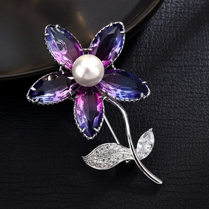Macro shot of purple crystal flower brooch with white pearl on black leather background