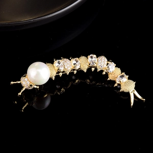 Macro shot of gold caterpillar brooch with white pearl head and sparkling zircon stones