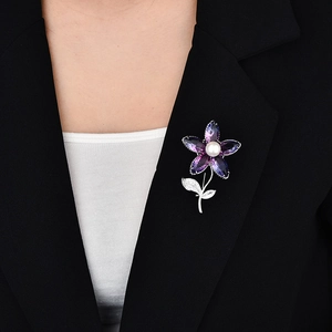Detail of floral brooch with purple crystals and pearl on a black suit jacket lapel