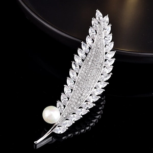 Gros plan sur une broche plume en argent avec zircone marquise et une perle blanche