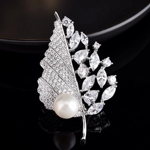 Macro detail of leaf brooch featuring shimmering zircons and a large white round pearl