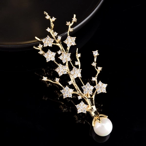 Vue macro détaillée d'une broche plante dorée avec des fleurs en zircon et une perle blanche