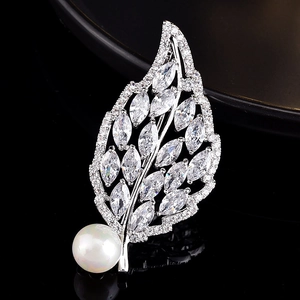 Macro detail of a silver leaf brooch with marquise zircons and a large white pearl inlay