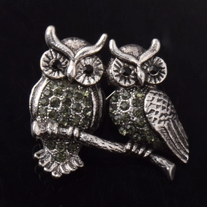 Gros plan de la broche hibou en argent rétro avec strass vert olive et yeux en pierre noire