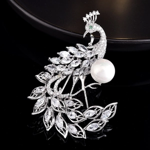Vue détaillée d'une broche paon avec zircones blancs et perle ronde sur fond noir brillant