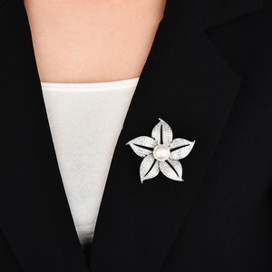 Elegant silver flower brooch with white pearl and sparkling crystals on a black suit lapel
