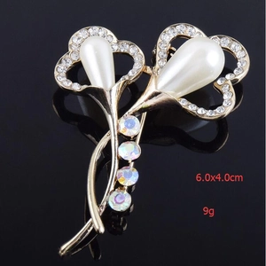 Vue détaillée de la broche fleur avec grandes perles gouttes et cristaux brillants sur or