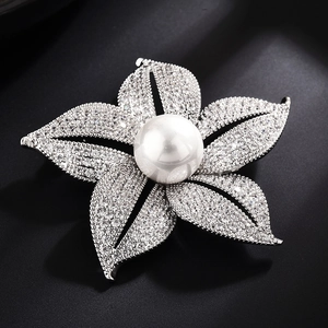 Elegant flower brooch with central pearl and zircon petals on a dark background