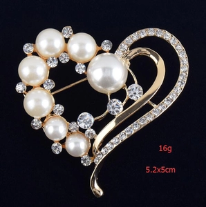 Détail macro d'une broche en forme de cœur avec perles et strass sur métal doré
