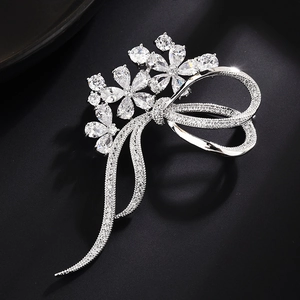 Detailed view of silver flower brooch with cubic zirconia crystals and ribbon bow design
