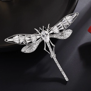 Élégante broche libellule en métal argenté avec cristaux de zircon sur fond noir mat