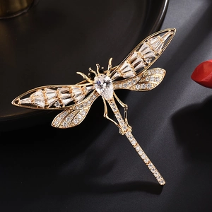 Élégante broche libellule dorée avec ailes en cristal et zircon poire sur fond noir mat