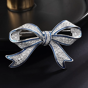 Broche élégante en forme de nœud avec alliage argenté, strass et bordures en émail bleu