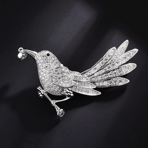 Macro shot of a silver bird brooch featuring sparkling white zircons on a dark background