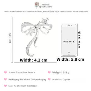 Broche nœud argentée avec zircons à côté d'un smartphone pour mesurer la taille