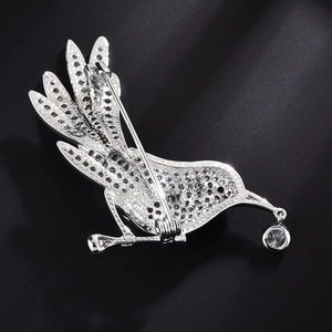 Silver bird brooch with pavé zircon settings and a round dangling pendant