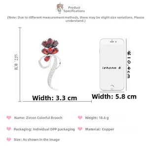 Detailed view of flower brooch with red zircons and size comparison to a smartphone