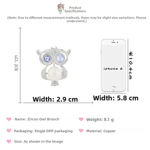 Détail de la broche hibou avec zircons bleus et perle, montrant l'échelle à côté d'un mobile
