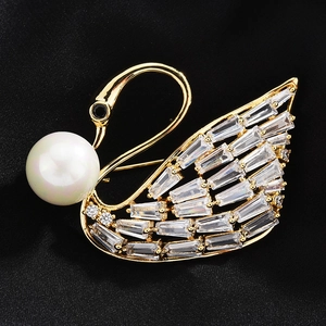 Macro shot of gold swan brooch featuring a large pearl and baguette-cut zircon wings
