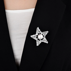 Detail of star-shaped brooch with white pearl and sparkling zircons on a black blazer