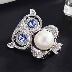 Broche chouette argentée avec yeux en pierres bleues et une grande perle blanche