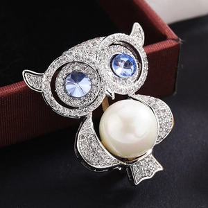 Élégante broche hibou avec ventre en perle et yeux en pierre bleue sur argent