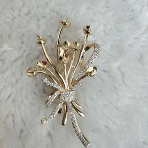 Détail d'une broche florale dorée sertie de zircons sur un fond en peluche blanche