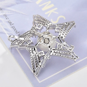 Star-shaped brooch with cubic zirconia and a central white pearl on a silver-toned metal base