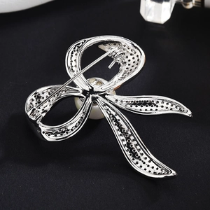 Eleganter silberner Schleifen-Anstecknadel mit Zirkon und Perle auf dunklem Grund