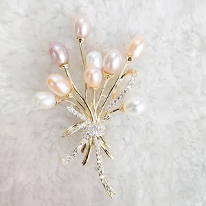 Élégante broche fleur en zircon doré avec perles d'eau douce multicolores sur fond en peluche