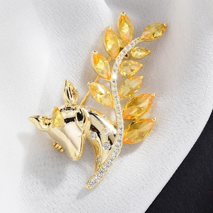 Eleganter Hirschkopf-Brosche in Gold mit gelben Zirkon-Blättern auf weißem Stoffhintergrund