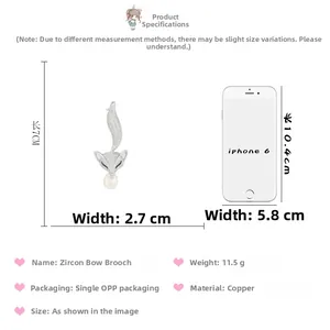Vue détaillée de la broche renard argentée avec zircons et perle à côté d'un iPhone