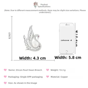 Detailed view of zircon swan brooch with a large pearl beside an iPhone 6 for size comparison