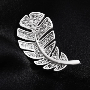 Elegant silver leaf brooch with shimmering cubic zirconia set on dark fabric background