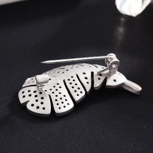 Back view of silver feather brooch showing safety pin clasp and matte leaf texture