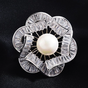 Elegant silver flower brooch with white pearl and sparkling crystals on black silk fabric