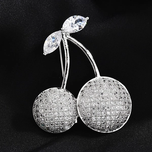 Elegant cherry brooch with sparkling zircons and silver finish on black fabric background