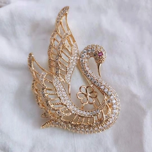 Détail d'une broche en forme de cygne doré avec pavé de zircons blancs et œil rubis