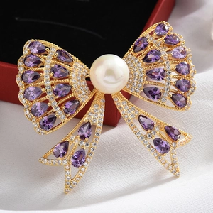 Macro detail of a golden bow brooch with a central pearl and purple pear-shaped crystals