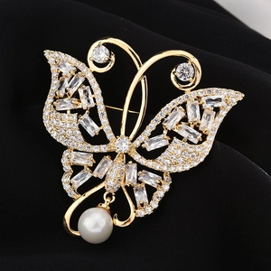Broche papillon dorée avec cristaux de zircone et perle blanche sur fond de soie noire